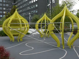 Wie Kunstobjekte wirken die gelben Klettergerüste des Spielbereichs auf dem Dach. Moderne Klettergerüste zum Spielen