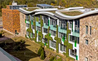 Optisch sind die grünen Wände sehr präsent und gewinnen besonderen Stellenwert dadurch, dass Jugendliche vor Ort in die Kultivierung einbezogen wurden. © Danil Kolodin / Tim Flynn architects Gebäude mit Vertikalbegrünung und begrüntem, geschwungenem Dach